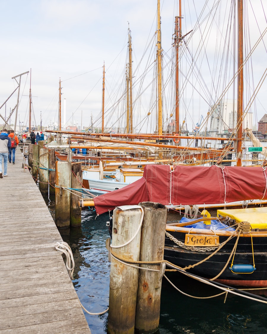 Wooden pier lined with traditional sailboats, people walking down the dock